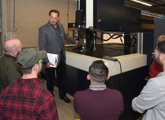 Turbine Technologies’ Max McIntyre shows Tunxis students high-precision machining of an aerospace part during their tour of the manufacturing facility. 