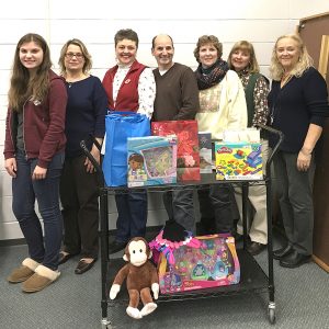 Pantry volunteers took a break from organizing and assembling with a few of the many items they gave away starting on Dec. 15. L to R are: Tunxis student Elizabeth Feest, Amy Feest, Colleen Richard, Ph.D., Peter Denegre, Judy Reilly Roberts, Kathy Golden and Maggie Carlin.  